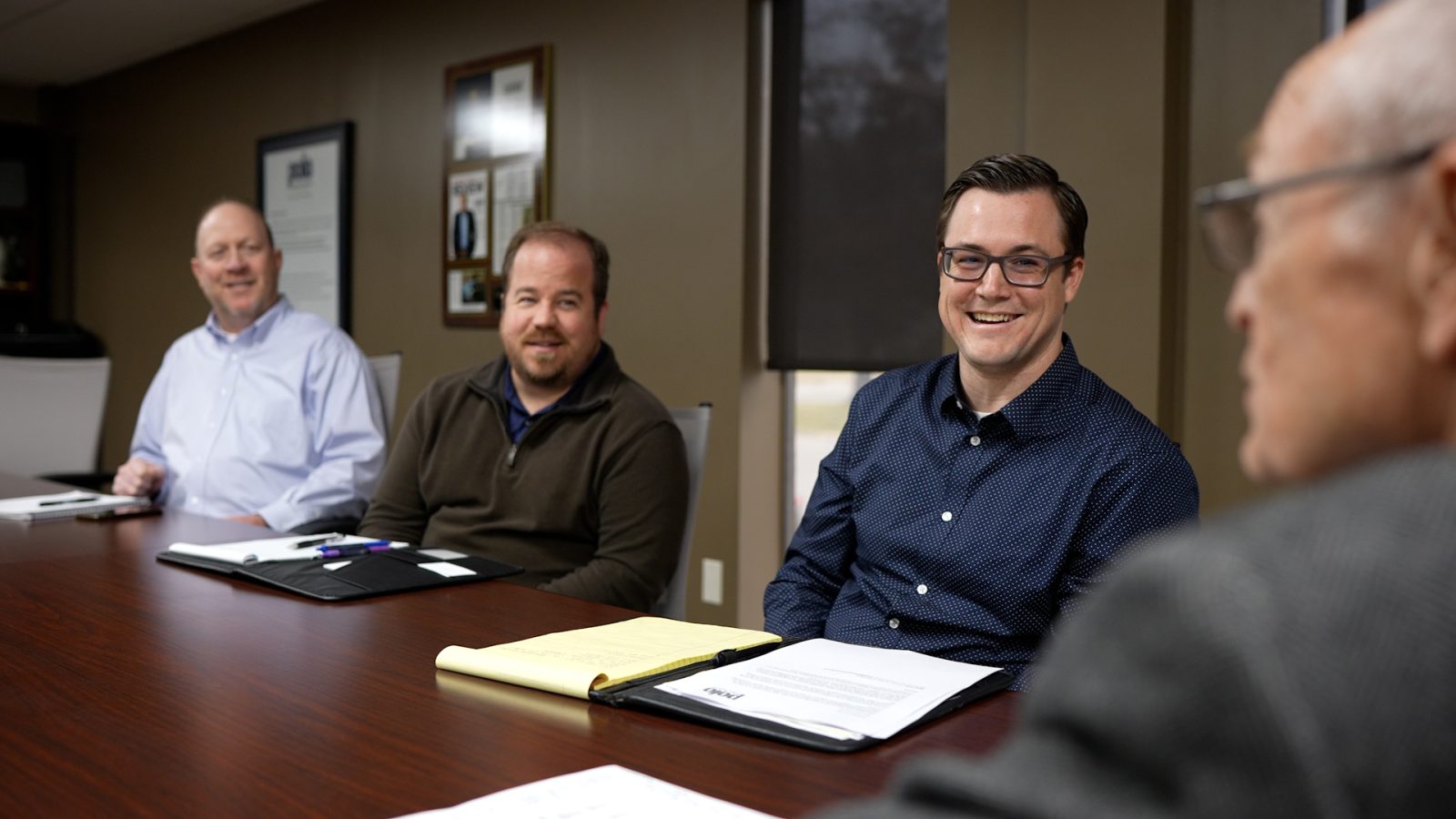 3 men smiling at conference table